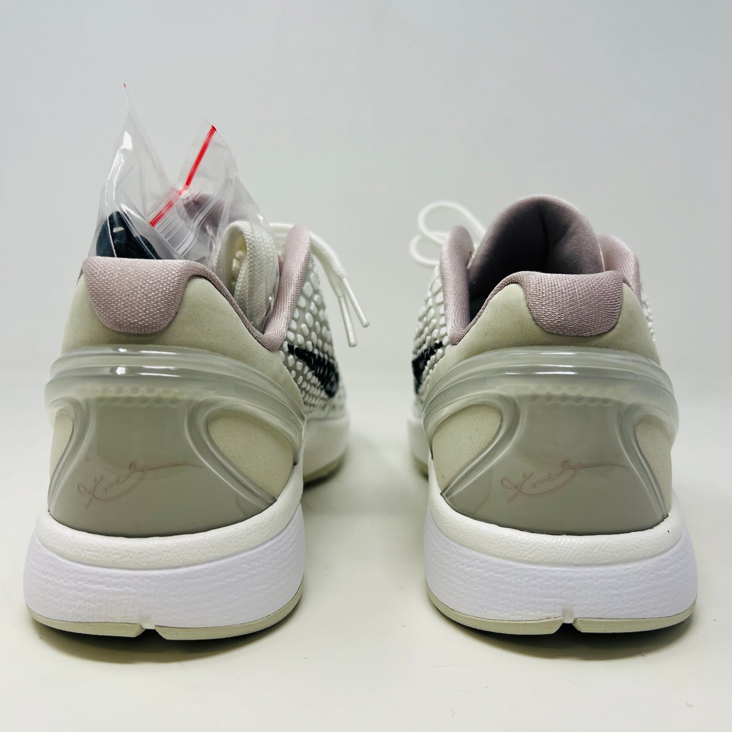 The fresh white Nike Kobe 6 Sail All-Star (GS) athletic shoe, showcasing a textured design and black swoosh logo, is presented on an orange box. Inside are plastic-wrapped accessories and extra laces for versatile style in 2024.