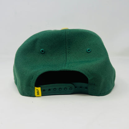 The Golf Wang New Era Camp Flog Gnaw 2018 Snap Back by Holy Ground Sneaker Shop features a green crown, yellow brim, and bold white/yellow G on the front. The brim sticker says 19 TWENTY and ADJUSTABLE.