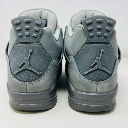 The Jordan 4 Retro SE Paris Olympics Wet Cement sneaker is displayed on its matching gray textured box, showcasing both in pristine condition. It features clean uppers with smooth and mesh textures, a visible air unit, and a size label with US, UK, and EU measurements.