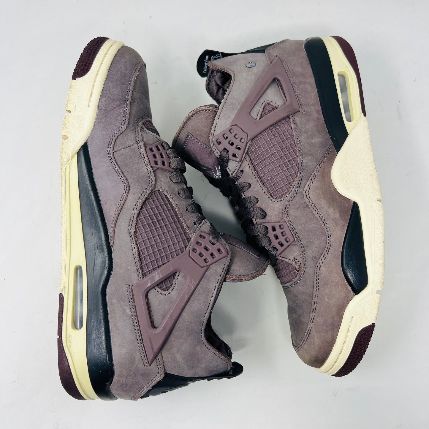 The Jordan 4 Retro SP A Ma Maniére Violet Ore sneakers sit elegantly on their matching box, featuring unique netting and black accents. The box displays size and brand details, emphasizing its immaculate condition.