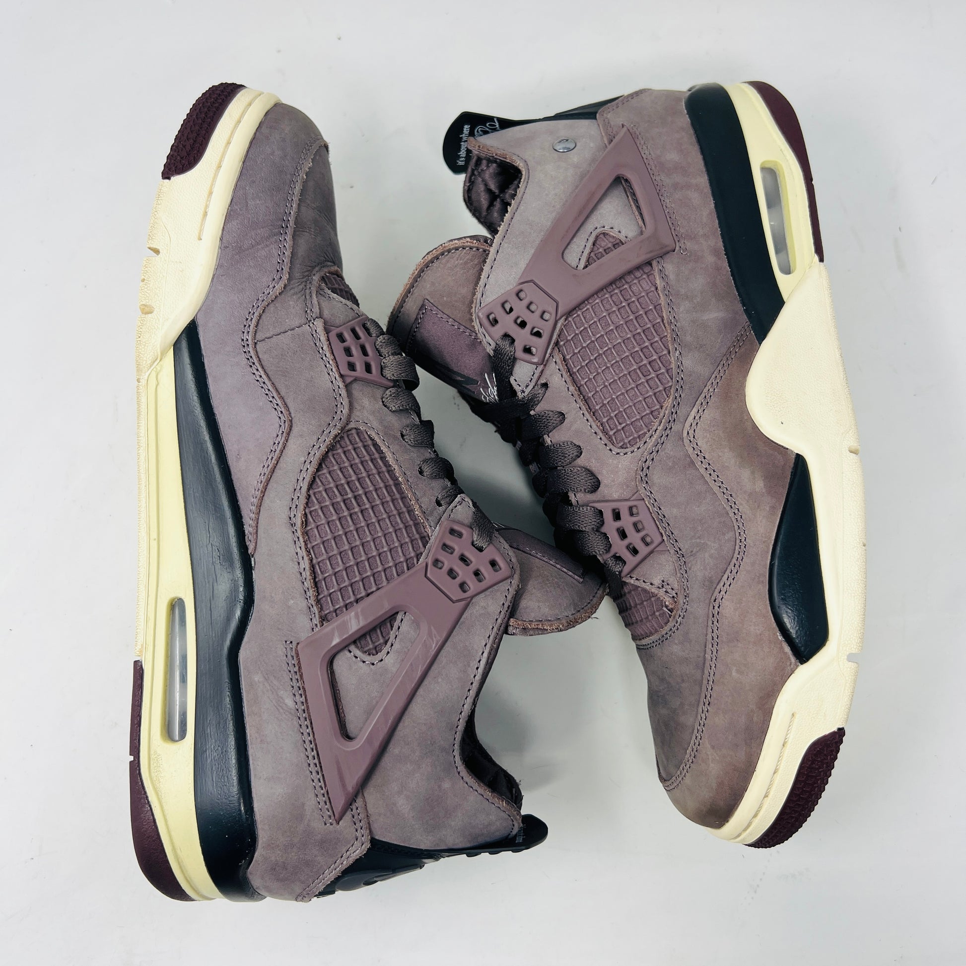 The Jordan 4 Retro SP A Ma Maniére Violet Ore sneakers sit elegantly on their matching box, featuring unique netting and black accents. The box displays size and brand details, emphasizing its immaculate condition.