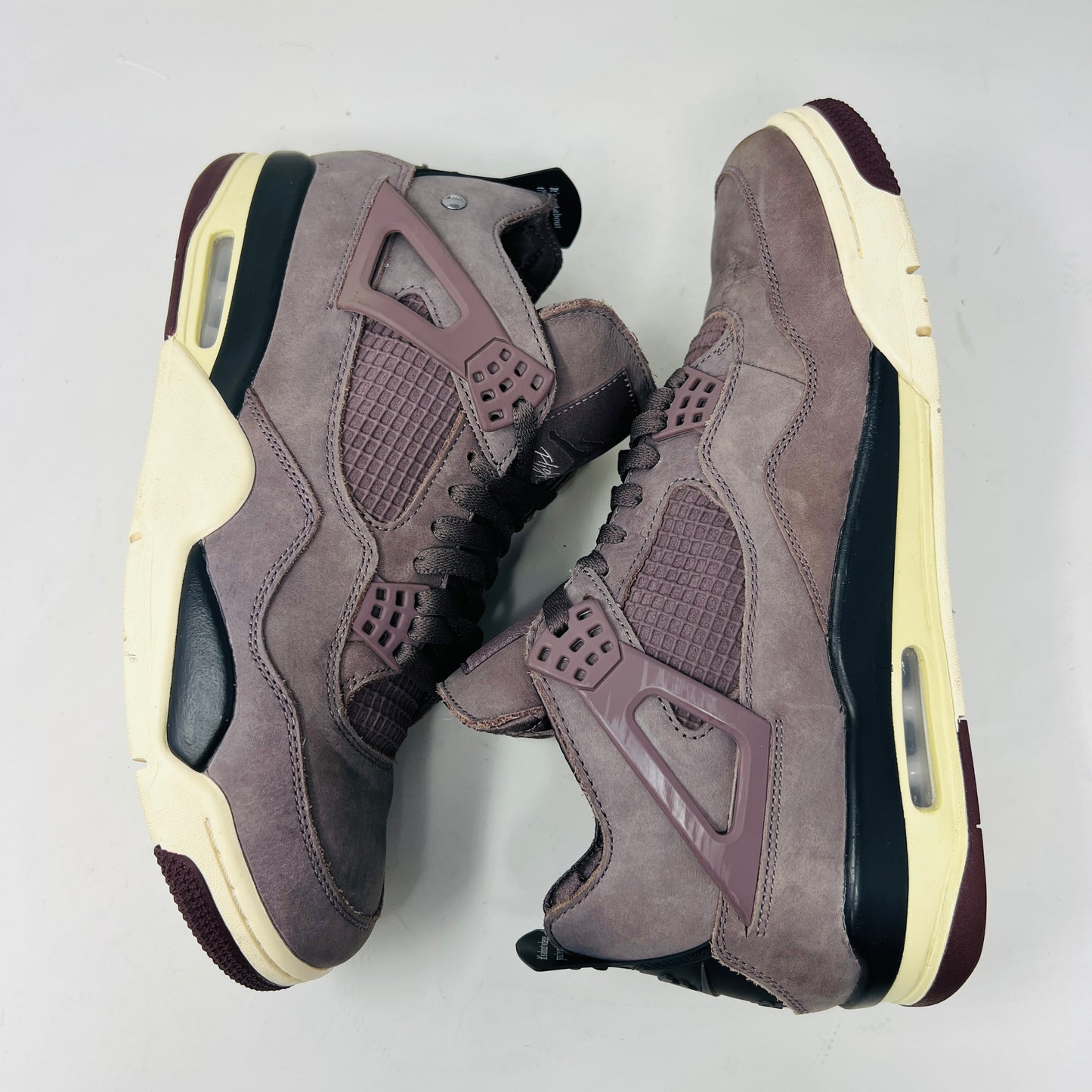 The Jordan 4 Retro SP A Ma Maniére Violet Ore sneakers sit elegantly on their matching box, featuring unique netting and black accents. The box displays size and brand details, emphasizing its immaculate condition.