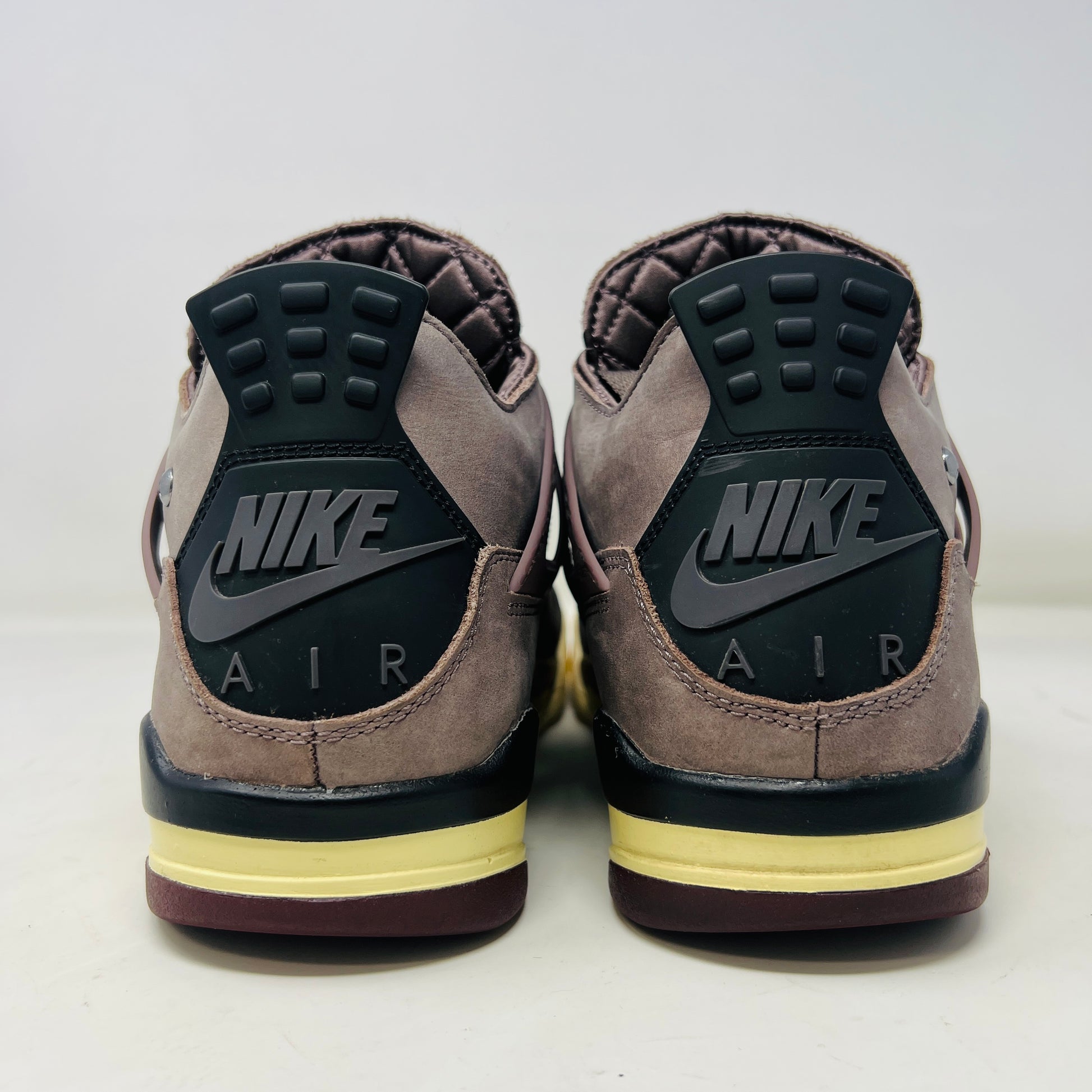 The Jordan 4 Retro SP A Ma Maniére Violet Ore sneakers sit elegantly on their matching box, featuring unique netting and black accents. The box displays size and brand details, emphasizing its immaculate condition.