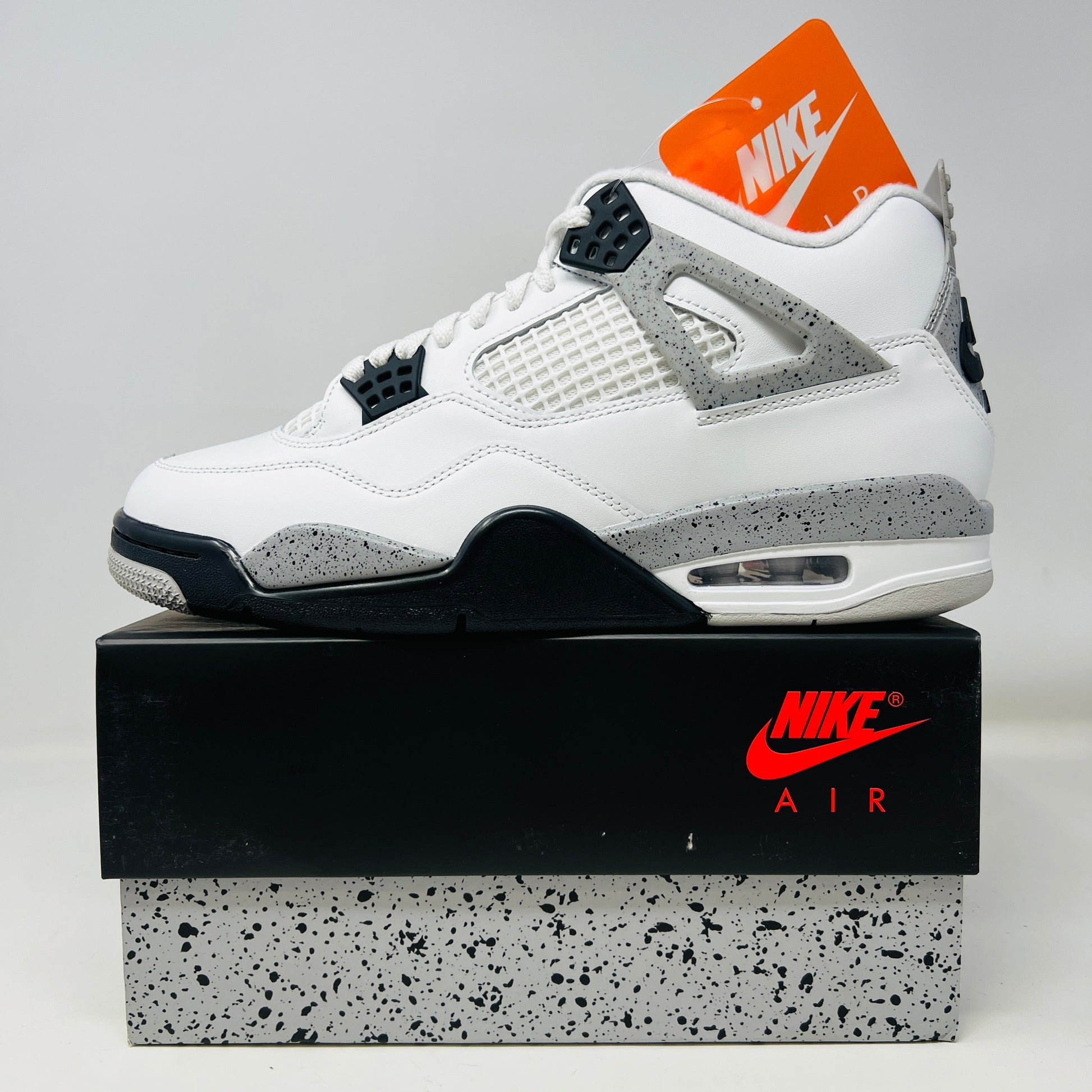 Jordan 4 Retro White Cement 2025 sneakers on speckled box, brand new condition.