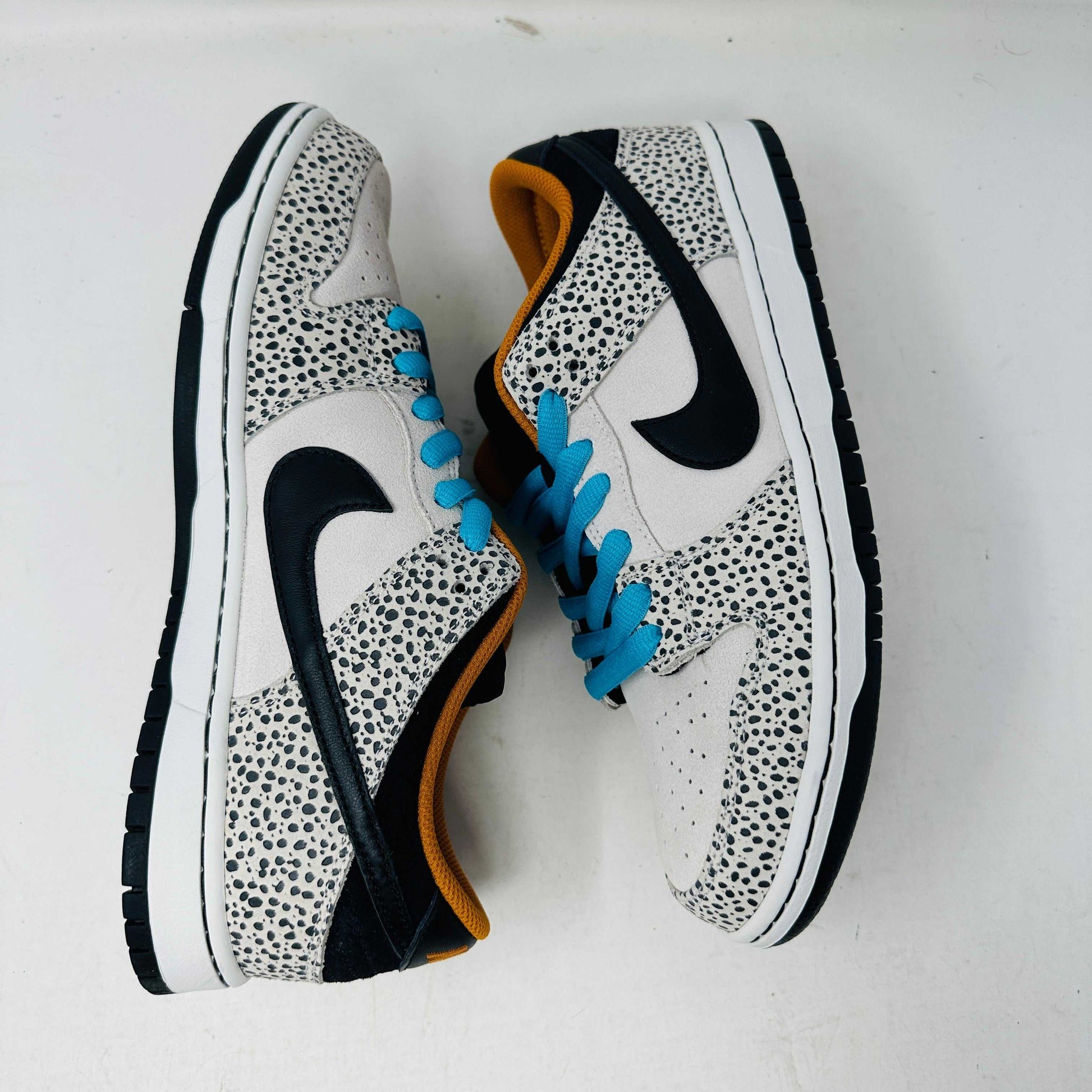 The Nike SB Dunk Low Electric Pack Olympic Safari, a new 2024 release, showcases a speckled gray and white design with a black swoosh, blue laces, and orange lining, elegantly set upon its box against a plain backdrop.