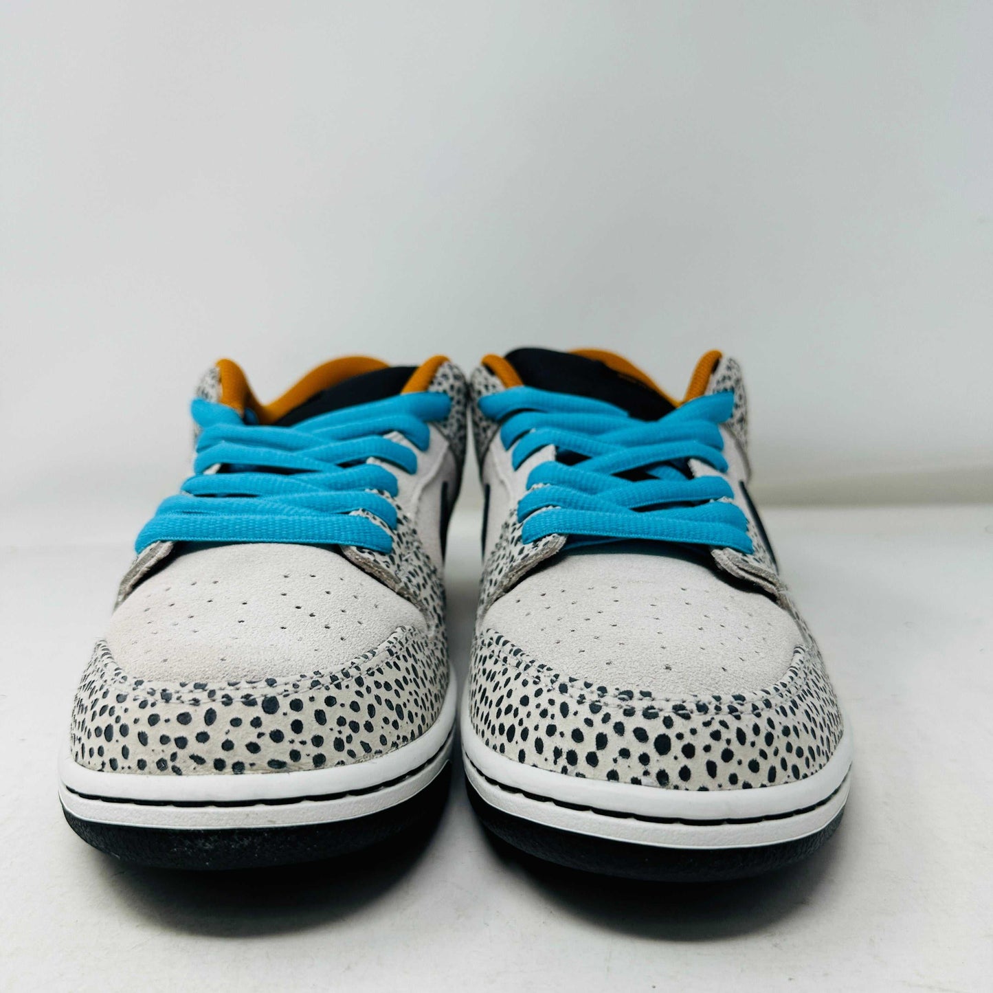 The Nike SB Dunk Low Electric Pack Olympic Safari, a new 2024 release, showcases a speckled gray and white design with a black swoosh, blue laces, and orange lining, elegantly set upon its box against a plain backdrop.