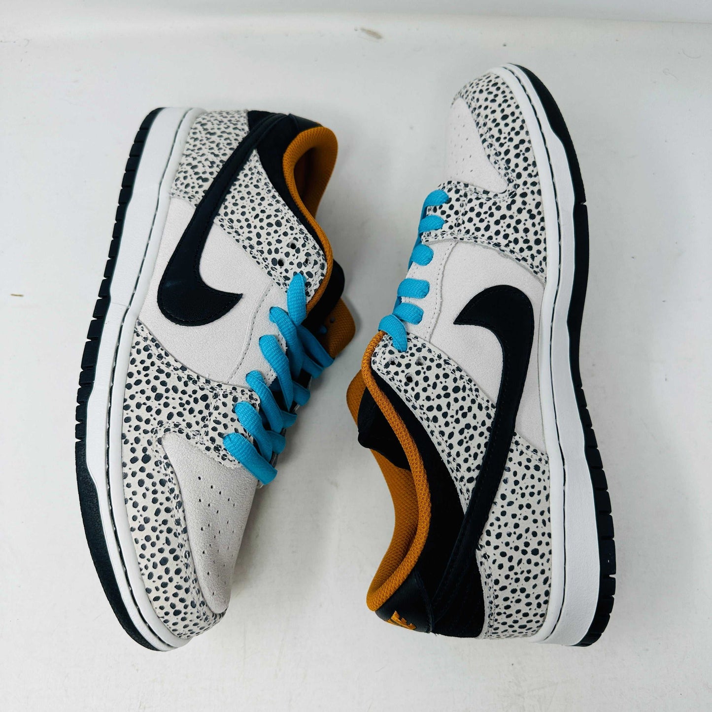 The Nike SB Dunk Low Electric Pack Olympic Safari, a new 2024 release, showcases a speckled gray and white design with a black swoosh, blue laces, and orange lining, elegantly set upon its box against a plain backdrop.