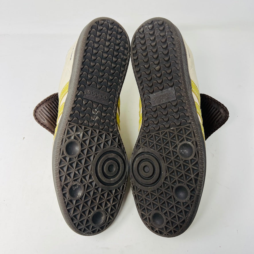 The 2023 adidas Samba Wales Bonner Ecrtin Brown sneakers feature beige uppers with three yellow stripes, a brown logo flap, and black soles. Despite general wear, the side and tongue branding stays distinct. Theyre displayed side by side on a white background.