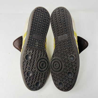 The 2023 adidas Samba Wales Bonner Ecrtin Brown sneakers feature beige uppers with three yellow stripes, a brown logo flap, and black soles. Despite general wear, the side and tongue branding stays distinct. Theyre displayed side by side on a white background.