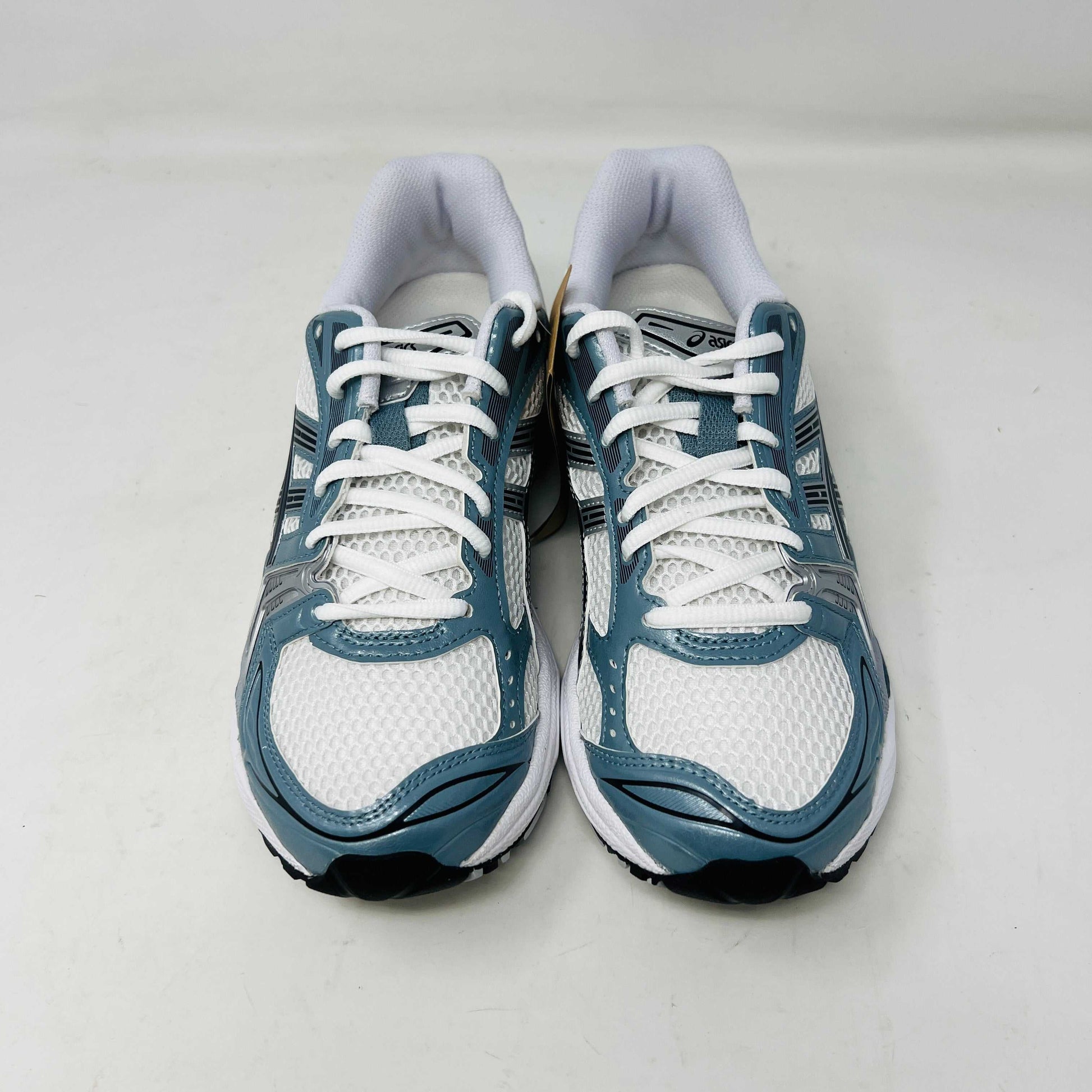 The ASICS Gel-Kayano 14 White Fjord Grey running shoe stands on a brown ASICS box, featuring intricate designs, a breathable mesh upper, and a cushioned thick sole for support. Its 100% authentic.