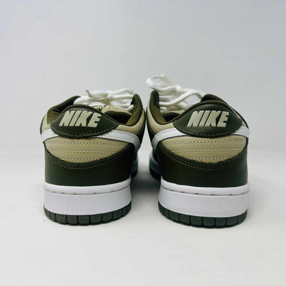 A Nike Dunk Low Light Stone shoe in green and beige with brand new white laces is displayed atop an orange Nike box. Extra white laces are in front, ensuring this 100% authentic pair from the Nike Dunk collection is ready to step out in style.