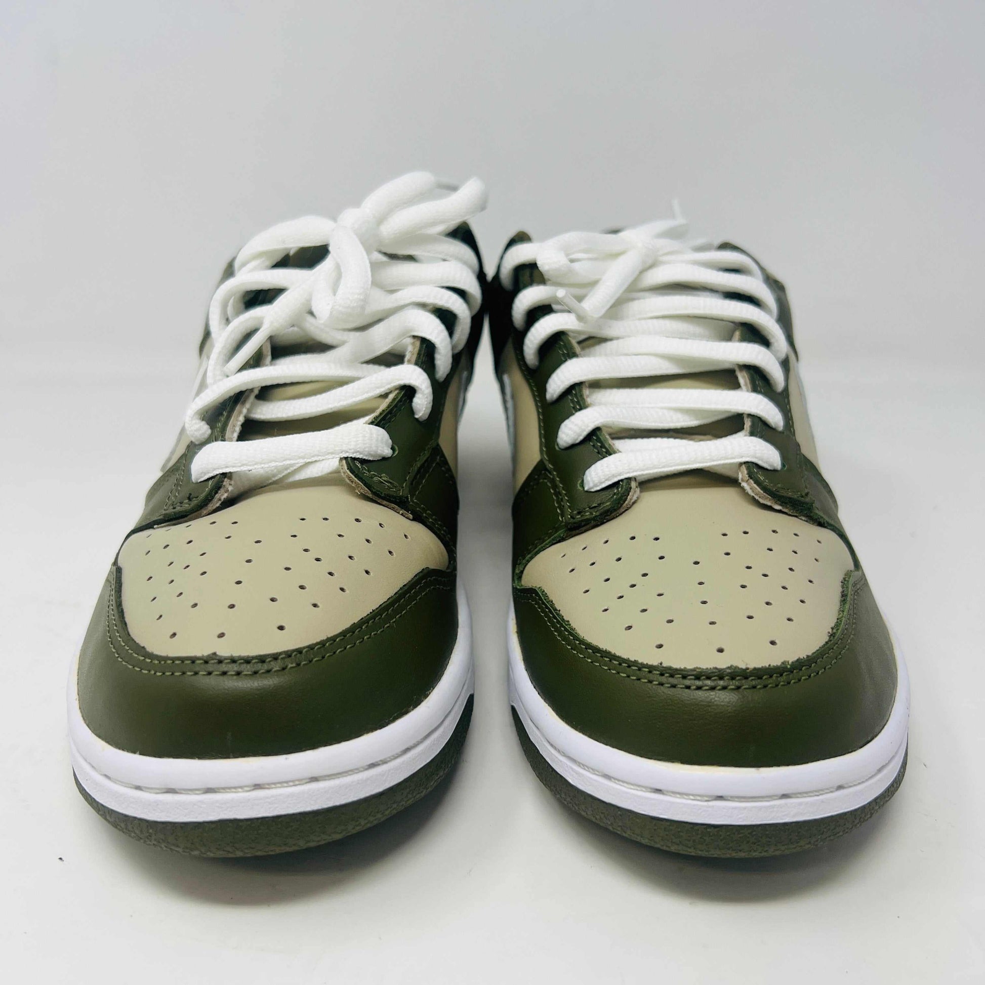 A Nike Dunk Low Light Stone shoe in green and beige with brand new white laces is displayed atop an orange Nike box. Extra white laces are in front, ensuring this 100% authentic pair from the Nike Dunk collection is ready to step out in style.