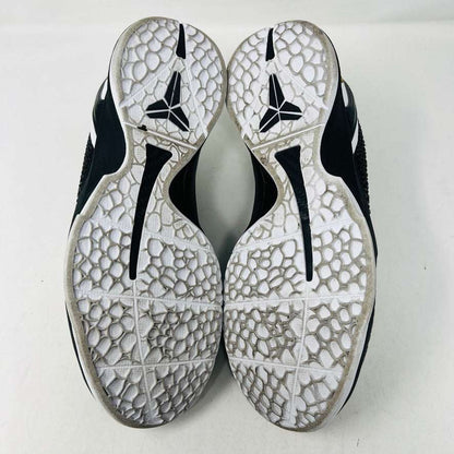 The KOBE Nike Kobe 6 Protro Mambacita Sweet 16 shoe, featuring clean black and white uppers, a white Swoosh, and a small gold 2 on the heel, is displayed on top of its black box with a Nike label. A sealed bag containing black laces accompanies the box for an authentic presentation.