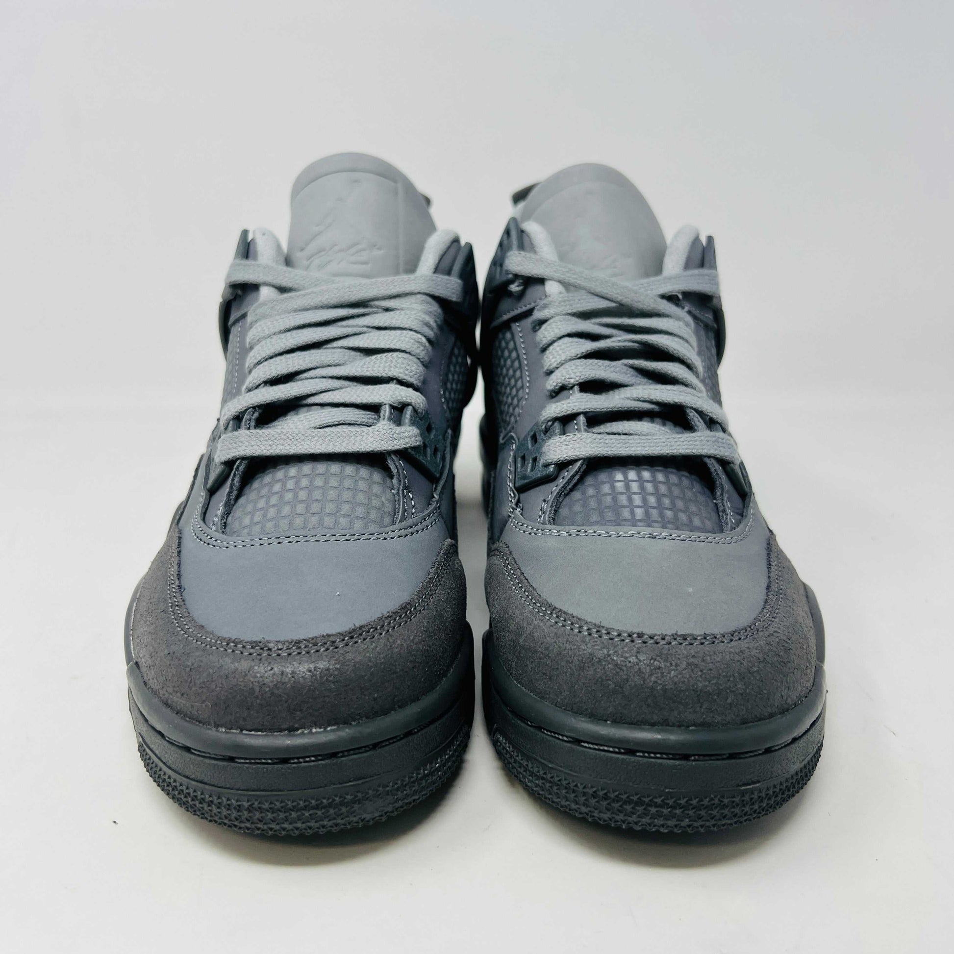 The Jordan 4 Retro SE Paris Olympics Wet Cement (GS), a brand-new gray sneaker, sits atop its pristine box. Featuring mesh and suede elements, it has a visible air unit in the midsole and a rubber outsole, poised to make an impression in 2024 against a plain white background.