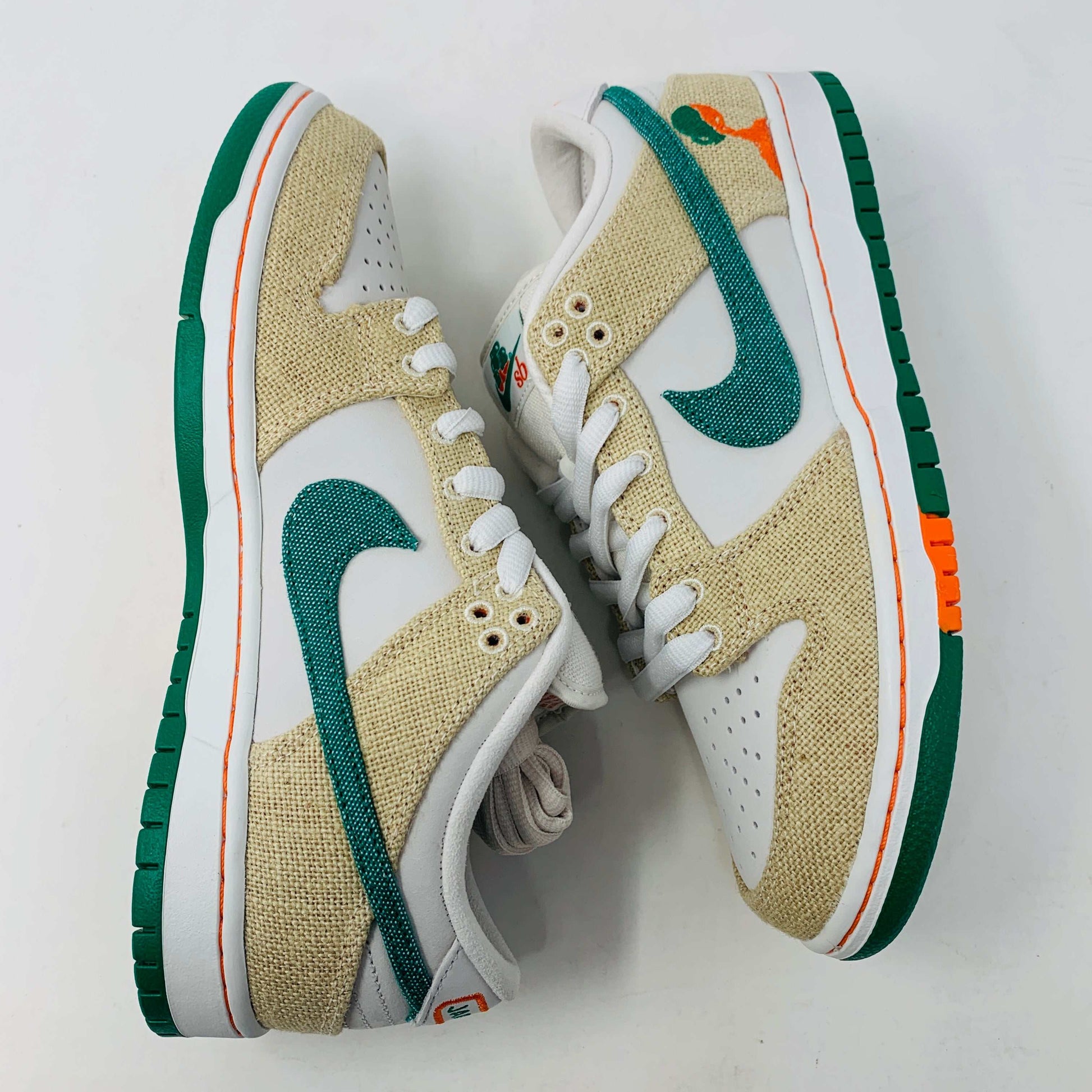 Front view of a brand new pair of Nike SB Dunk Low Jarritos sneakers in beige and white with green accents, featuring textured beige material, perforated toe panels, white laces, and swoosh logos on the tongues. Extra 2 laces included; displayed on a plain white background.
