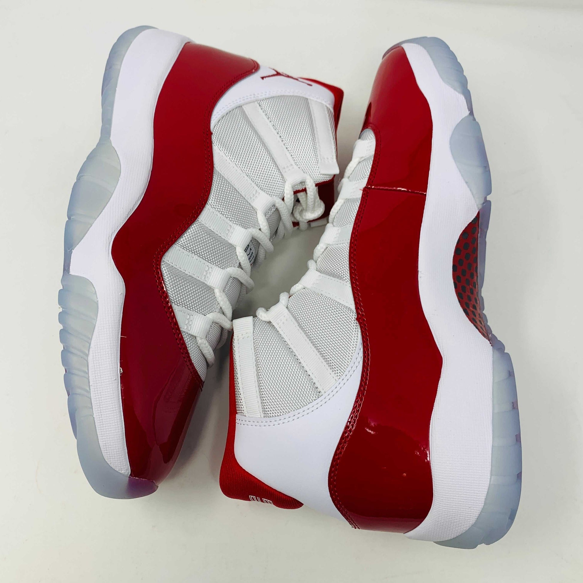 Jordan 11 Retro Cherry (2022) sneakers with white and red colorway, patent leather mudguard, and full-length Air-Sole unit.