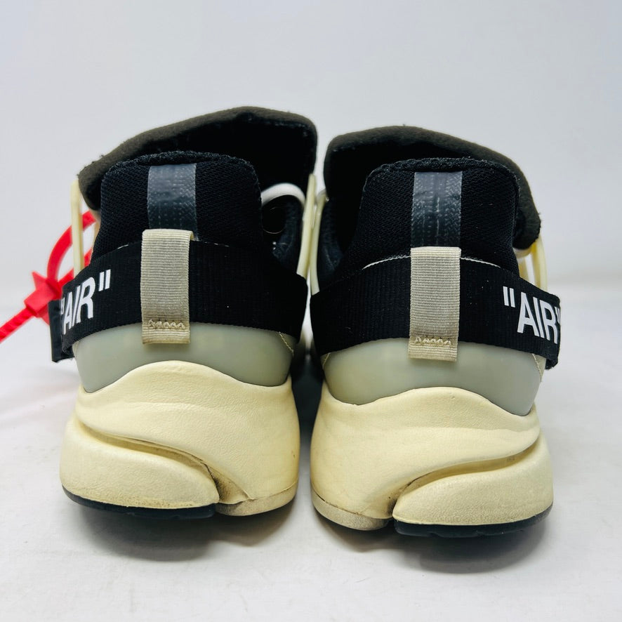 The 2017 classic Nike Air Presto Off-White features a black sneaker with white laces, a red tag, iconic AIR text, and an edgy zip tie. Displayed on its box, it includes extra black, neon green, and orange laces labeled SHOELACES.
