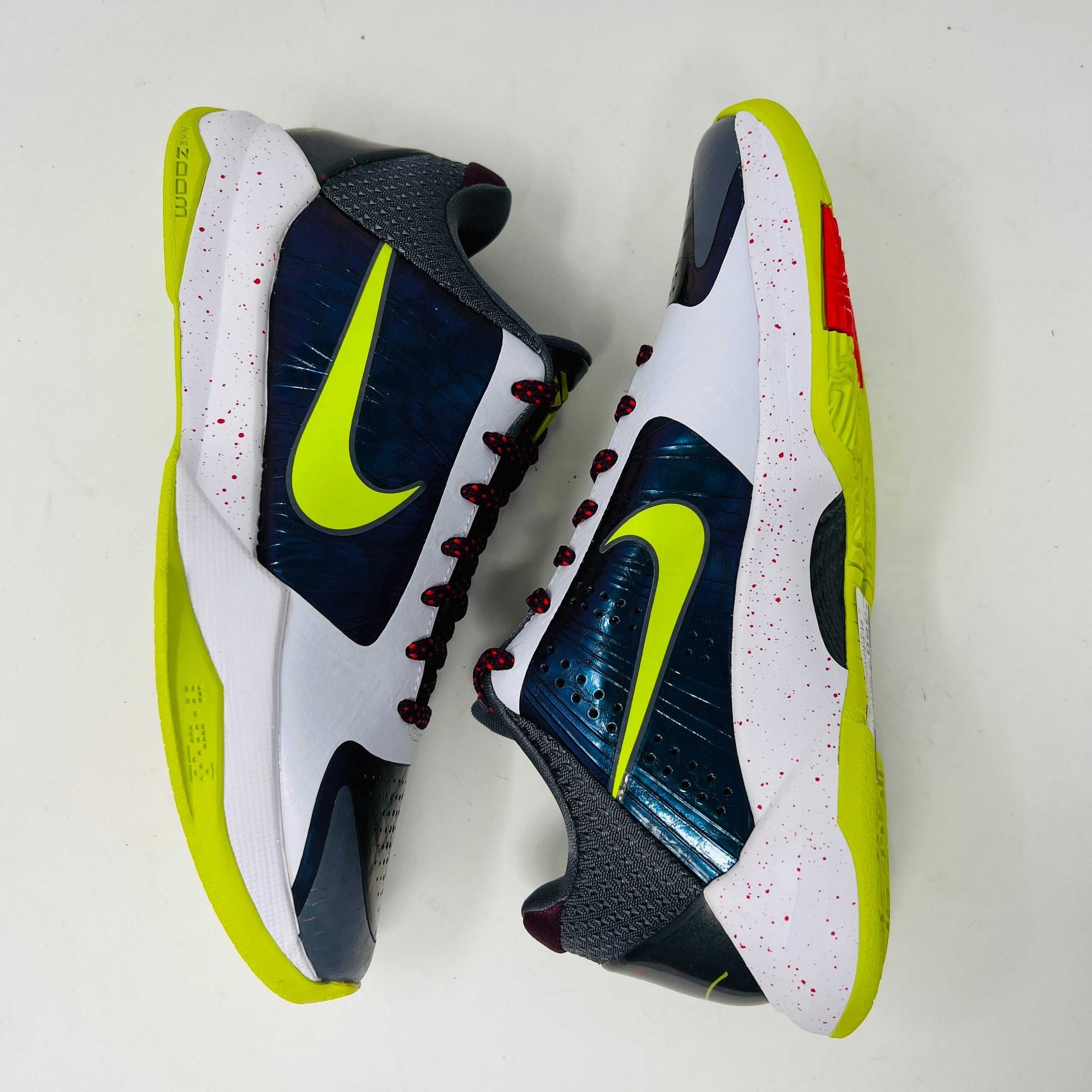 The Nike Kobe 5 Protro Chaos sneaker, authentic and vibrant, is showcased on a black shoe box. It features a bright lime green Nike swoosh, purple and white accents, a speckled pink midsole, red-speckled laces, and a textured gray heel.
