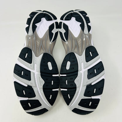 A brand new pair of ASICS GT-2160 JJJJound White sneakers, featuring mesh details and black stripes, is displayed on a black ASICS shoe box with extra laces in front for a complete authentic look.
