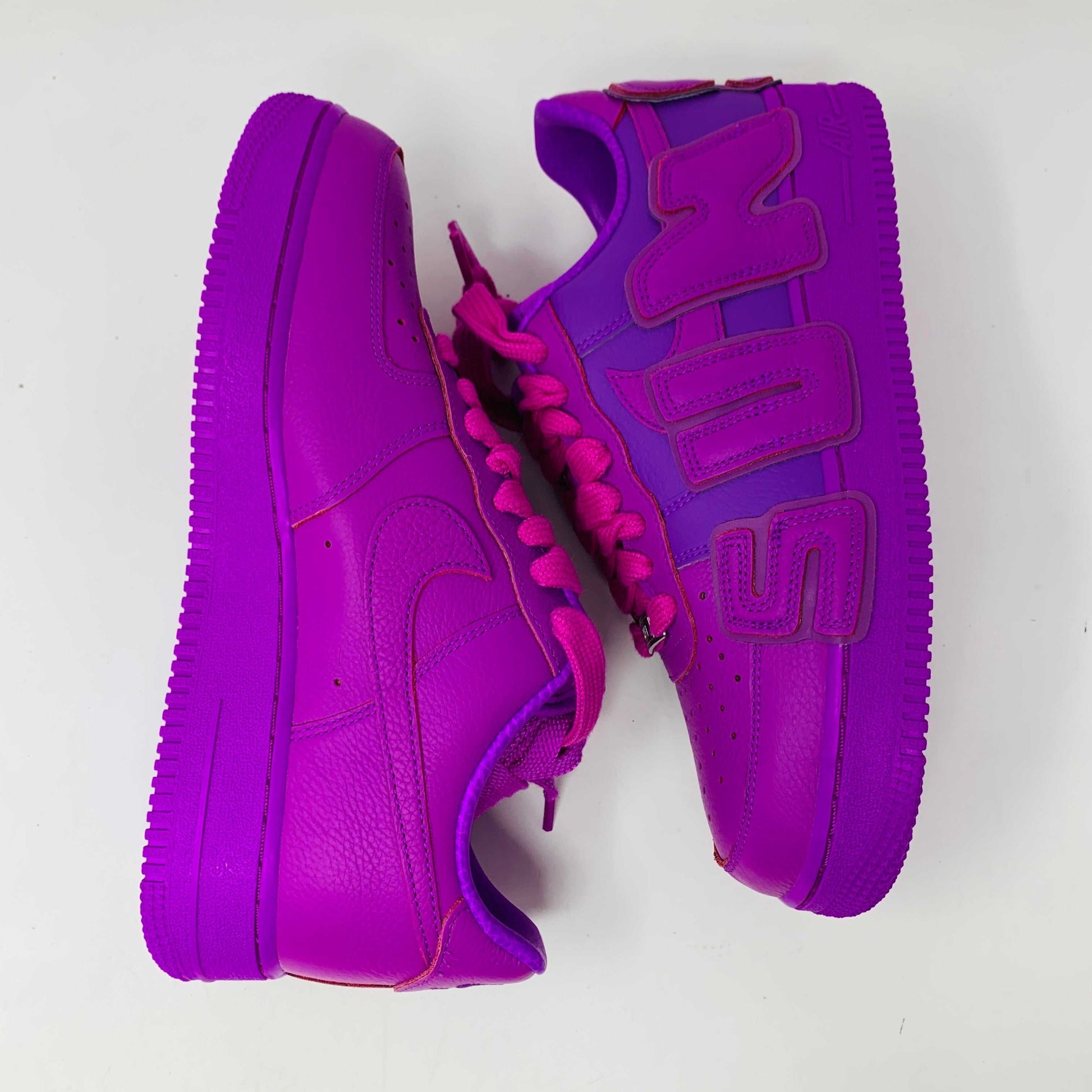 The Nike Air Force 1 Low Cactus Plant Flea Market Fuchsia Dream sneaker, vibrant pink with oversized SUN lettering, boldly sits on a black box featuring the iconic white swoosh. This brand new, 100% authentic pair includes extra laces and is presented against a plain white background.