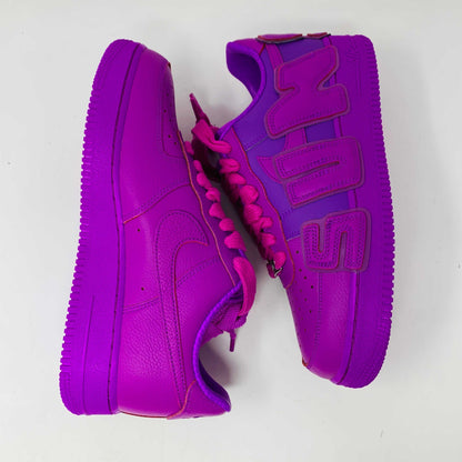 The Nike Air Force 1 Low Cactus Plant Flea Market Fuchsia Dream sneaker, vibrant pink with oversized SUN lettering, boldly sits on a black box featuring the iconic white swoosh. This brand new, 100% authentic pair includes extra laces and is presented against a plain white background.