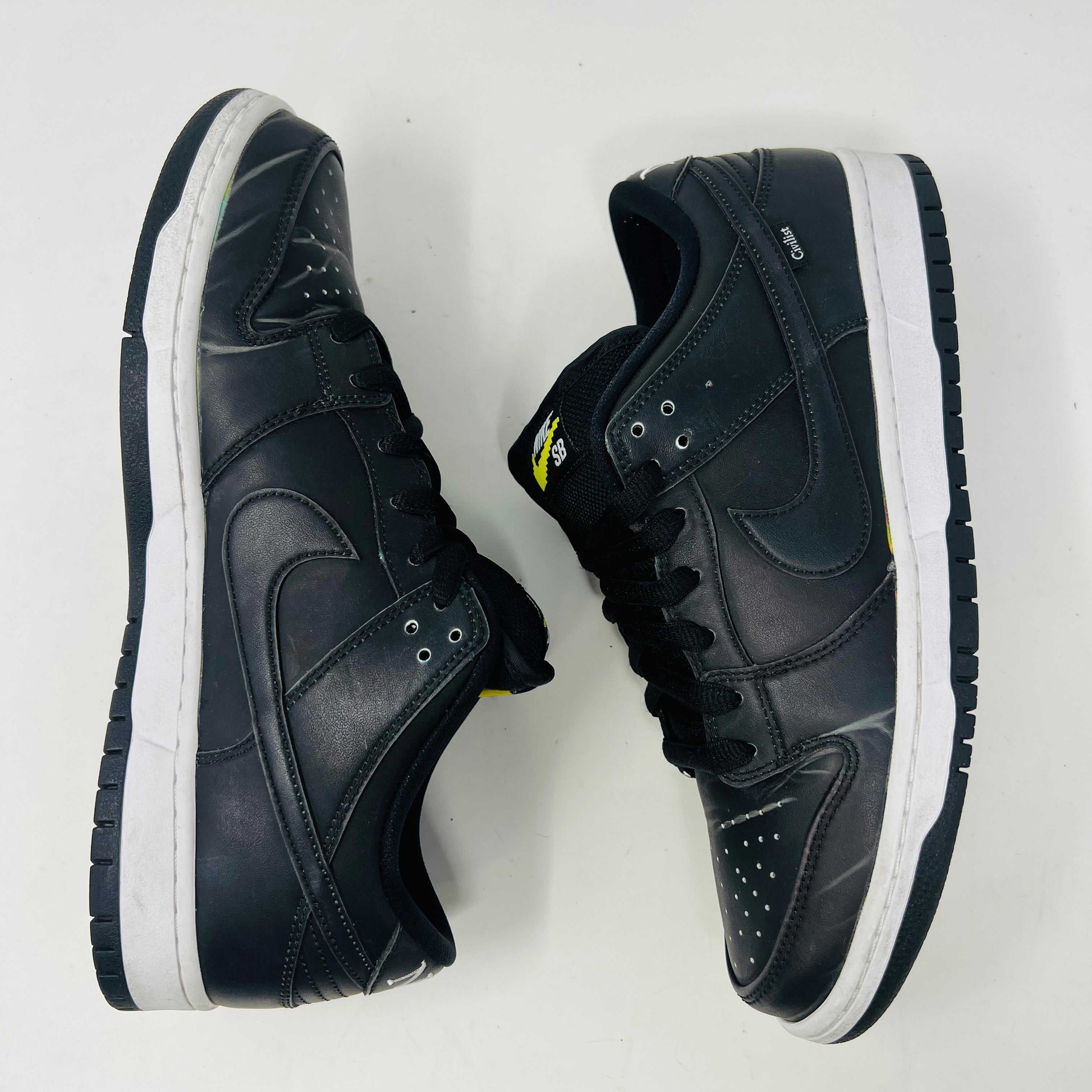 Nike SB Dunk Low Civilist sneakers, black with white soles and yellow tongue details, showcased on a white backdrop. They blend style and comfort effortlessly, making them a standout in 2020 sneaker collections.
