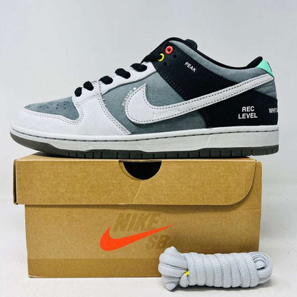 Nike SB Dunk Low sneaker in grey, white, and black with colorful eyelets and text detailing, displayed with extra grey laces and box.