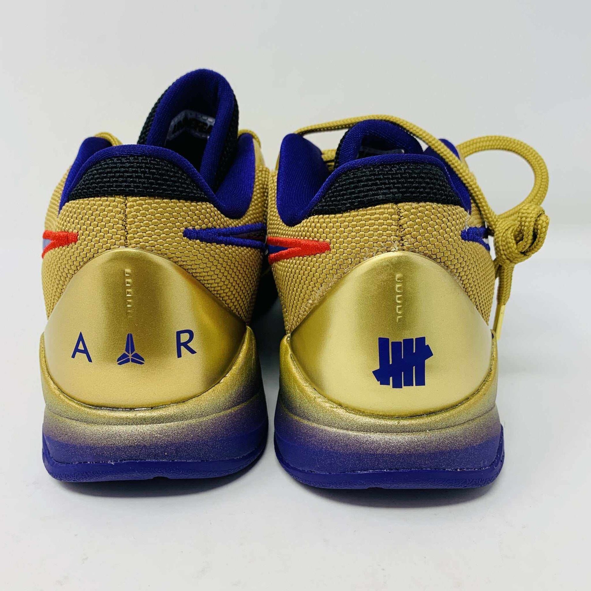 The Nike Kobe 5 Protro Undefeated Hall of Fame sneaker features a gold and purple design with a red swoosh, numbers 24 10 8 on the side, and comes with extra purple laces atop an orange box—100% authentic and perfect for any collection.