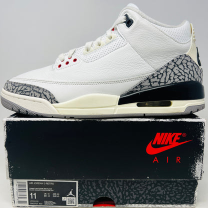 The Jordan 3 Retro White Cement Reimagined features white uppers with gray elephant print and red details, displayed on a black Nike Air shoebox. The size on the box reads 11, and the sneakers are pristine, free from heel drag.