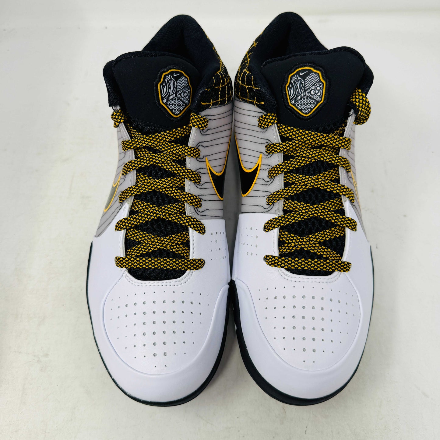 The Nike Kobe 4 Protro White Black Del Sol is a brand-new, authentic Nike sneaker on a shoebox. Predominantly white, it features black and yellow accents with a swoosh logo, a black sole, and yellow-speckled laces, designed for performance and comfort.