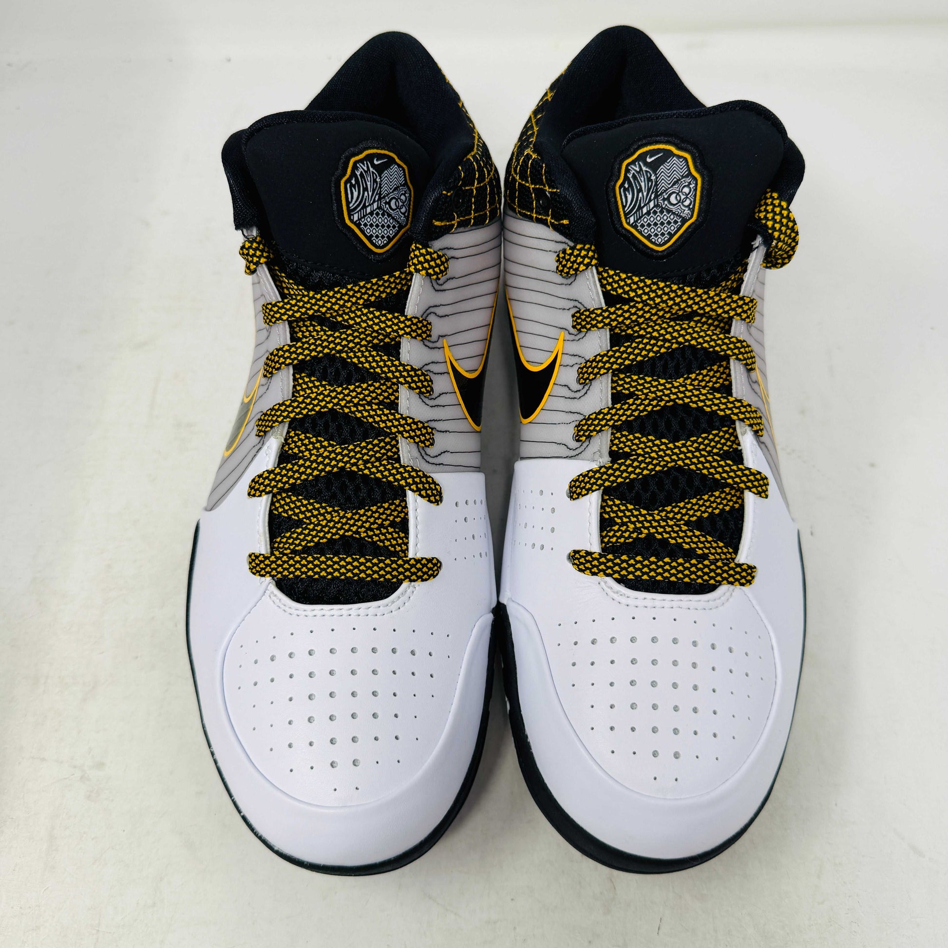The Nike Kobe 4 Protro White Black Del Sol is a brand-new, authentic Nike sneaker on a shoebox. Predominantly white, it features black and yellow accents with a swoosh logo, a black sole, and yellow-speckled laces, designed for performance and comfort.