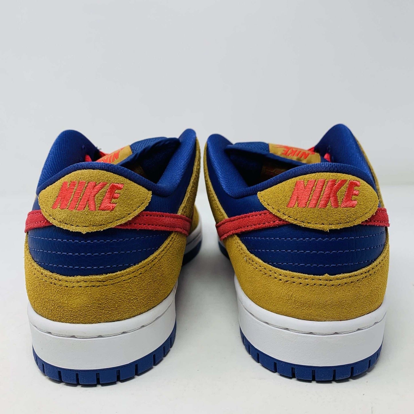 The Nike SB Dunk Low Reverse Papa Bear features a blue and yellow suede upper, a red Swoosh, and orange laces. It comes with extra yellow laces in front of its purple Nike SB box and is 100% authentic.