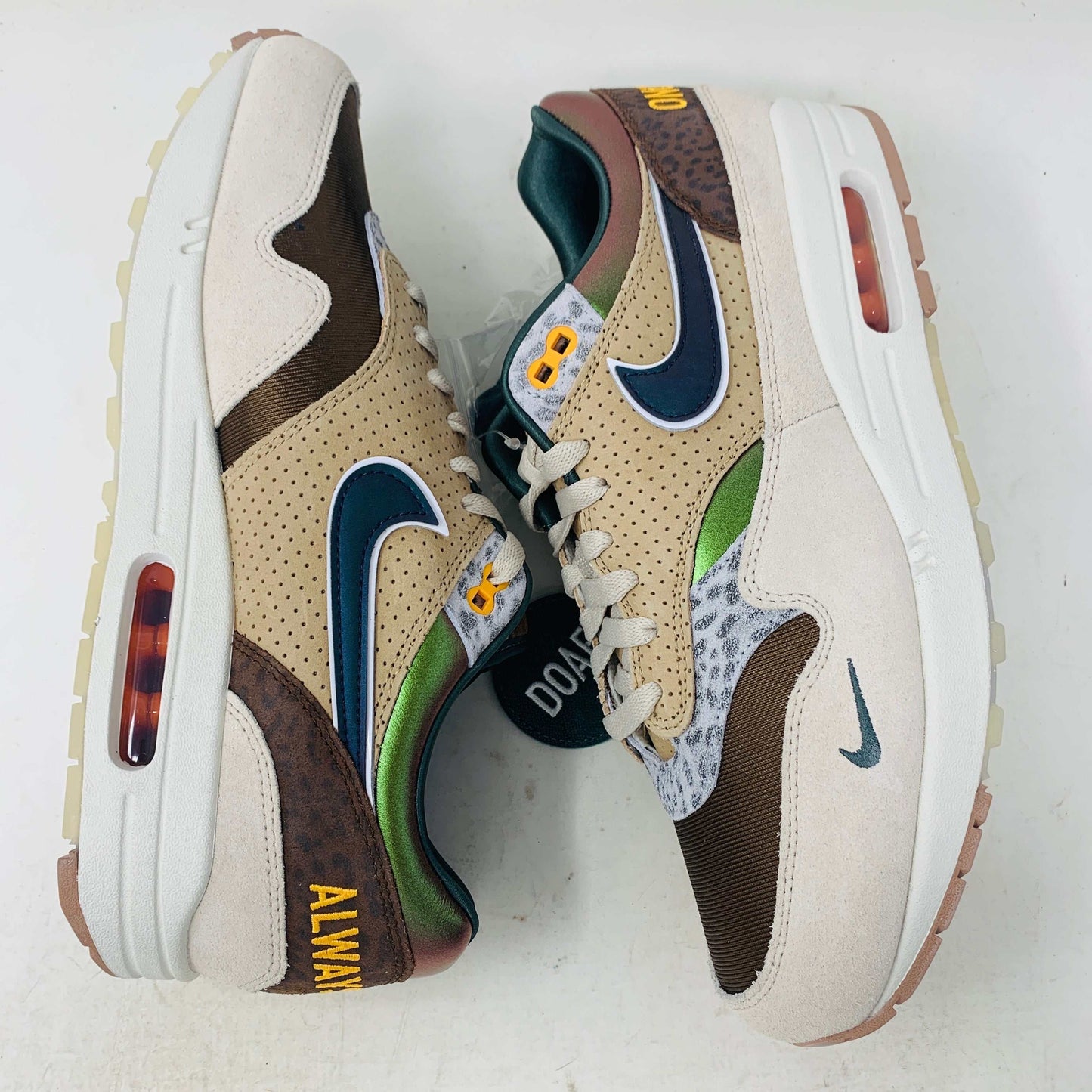 The Nike Air Max 1 87 Premium University of Oregon PE (2024) is a stylish, brand new sneaker featuring a blend of beige, purple, and leopard print with perforated and smooth leather textures. It comes in a vibrant green box and includes a visible air unit in the sole.