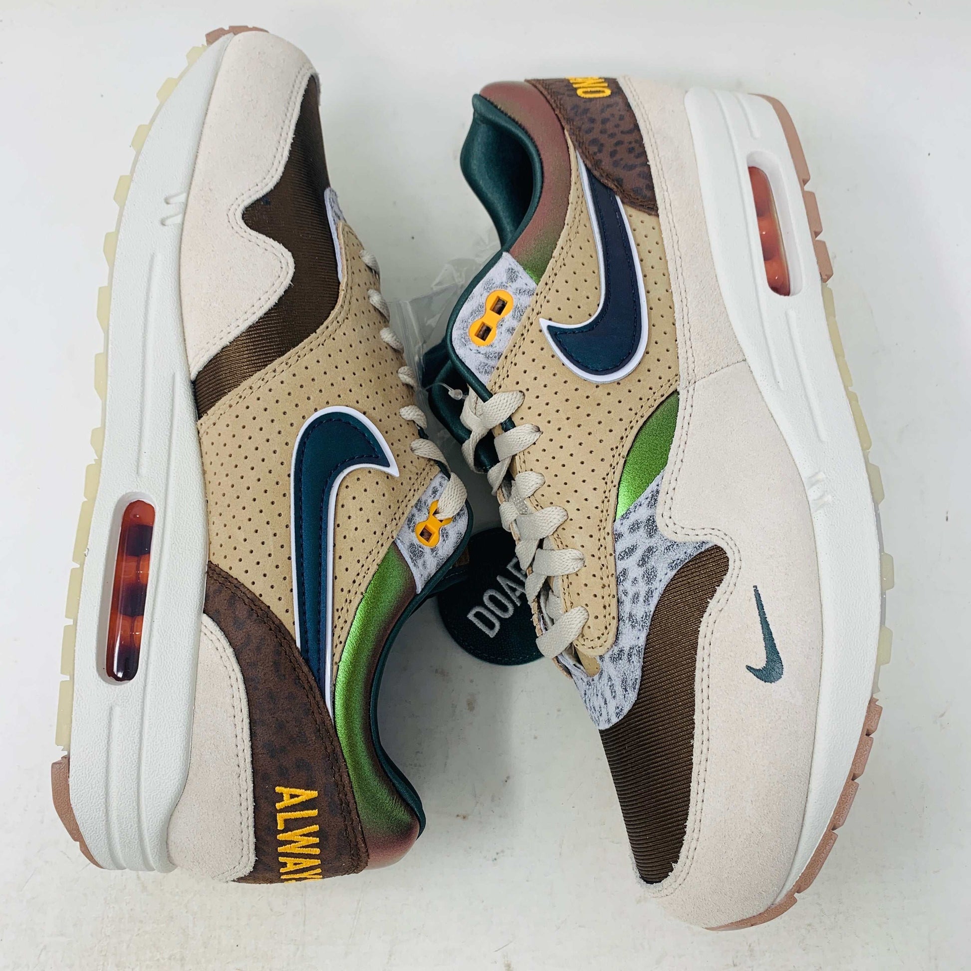 The Nike Air Max 1 87 Premium University of Oregon PE (2024) is a stylish, brand new sneaker featuring a blend of beige, purple, and leopard print with perforated and smooth leather textures. It comes in a vibrant green box and includes a visible air unit in the sole.