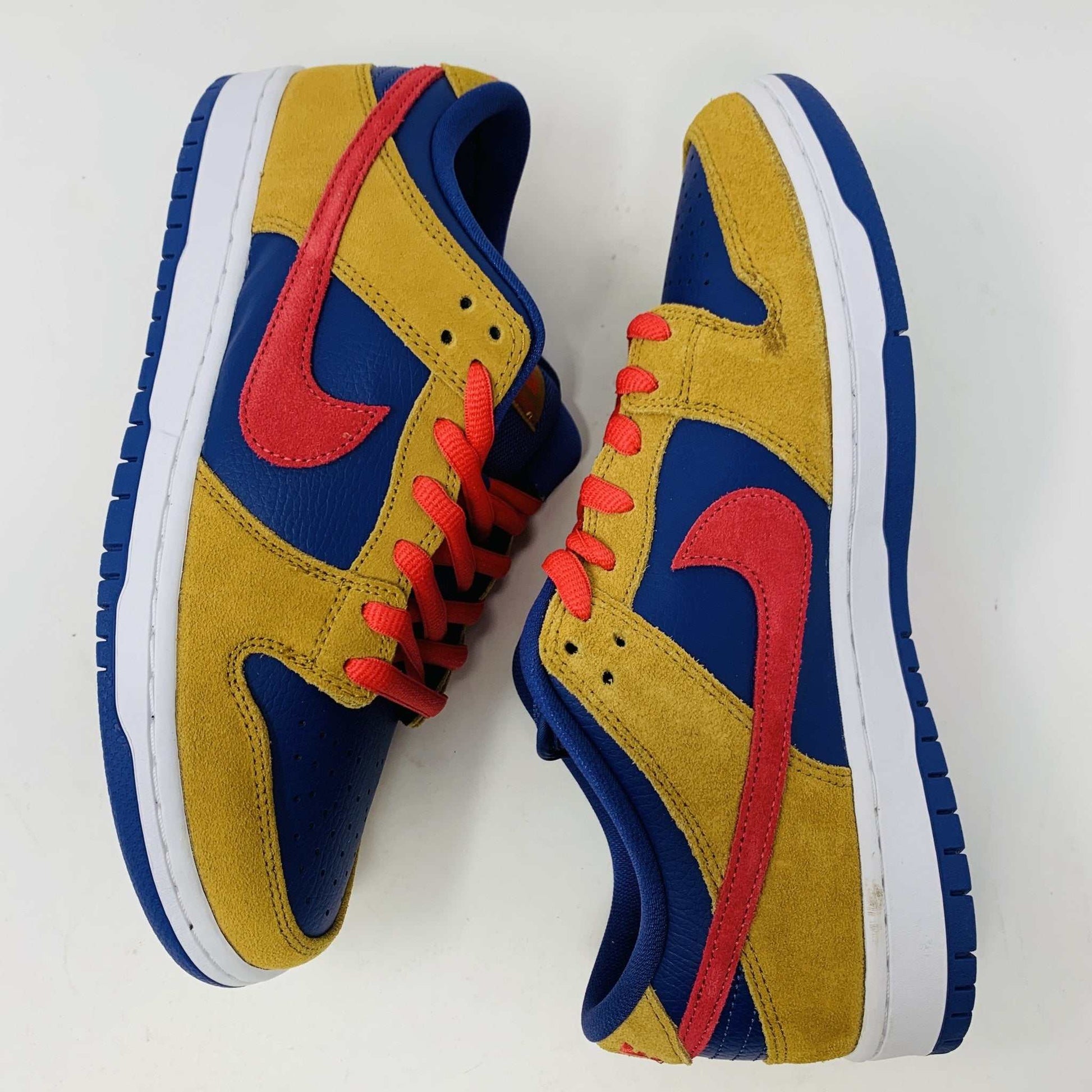 The Nike SB Dunk Low Reverse Papa Bear features a blue and yellow suede upper, a red Swoosh, and orange laces. It comes with extra yellow laces in front of its purple Nike SB box and is 100% authentic.