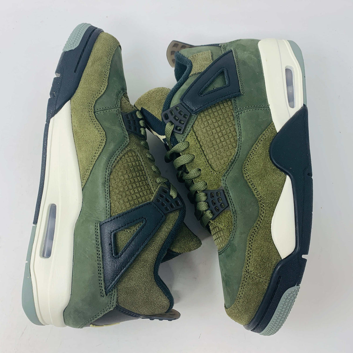 The Jordan 4 Retro SE Craft Medium Olive sneakers feature a blend of green, black, and white with a mesh and suede texture. Elegantly presented on a green shoebox against a white backdrop, they epitomize 100% authentic craftsmanship by Jordan.
