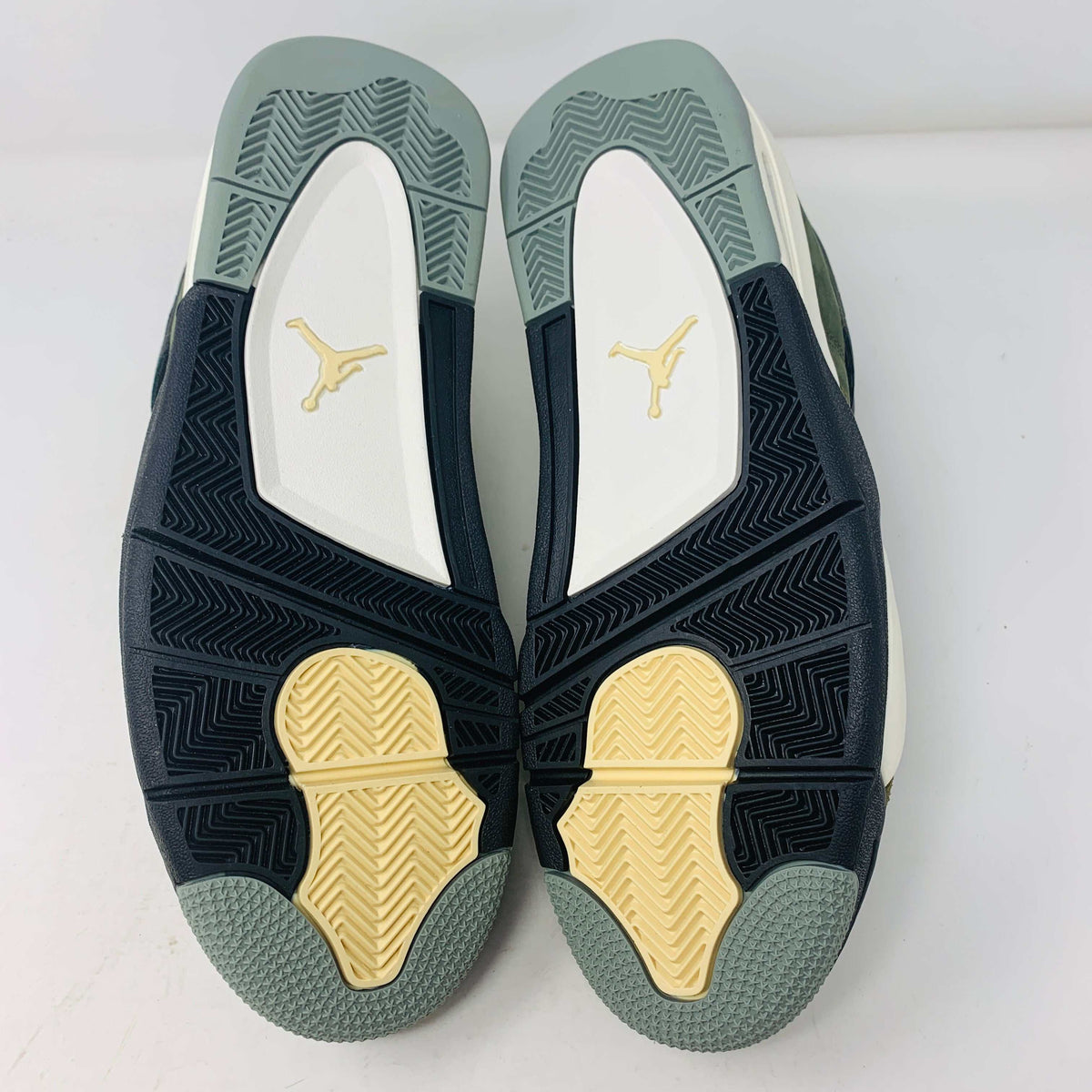 The Jordan 4 Retro SE Craft Medium Olive sneakers feature a blend of green, black, and white with a mesh and suede texture. Elegantly presented on a green shoebox against a white backdrop, they epitomize 100% authentic craftsmanship by Jordan.