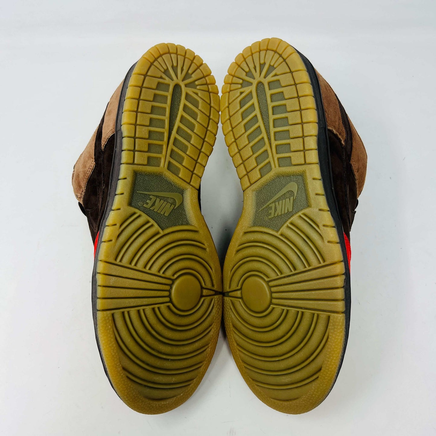 A pair of BRAND NEW Nike SB Dunk Low Bison sneakers featuring brown and red suede uppers, black laces, EXTRA LACES included, and a light brown sole. Positioned side by side on a white background, they promise to be 100% authentic and stylish.