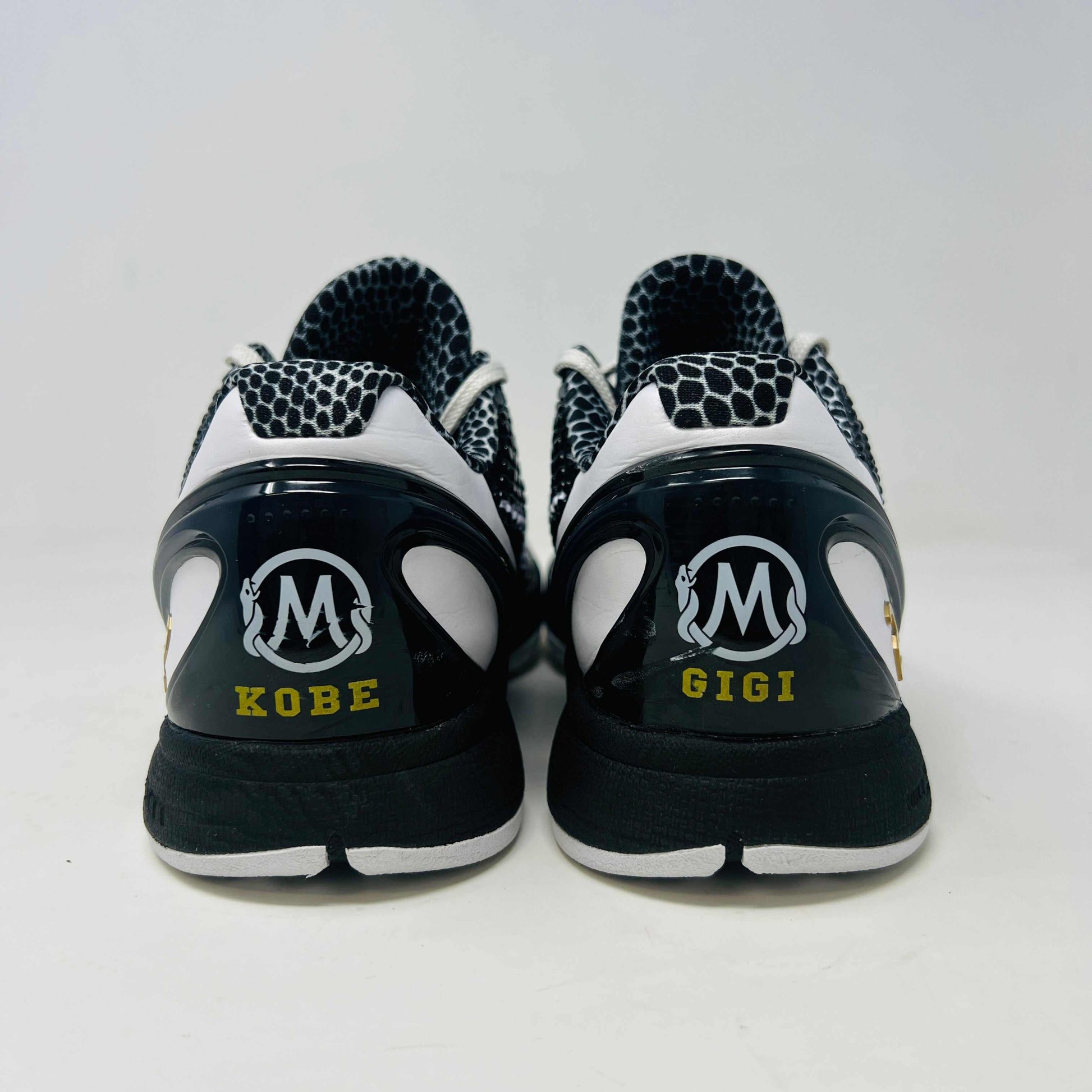 The black and white Nike Kobe 6 Protro Mambacita Sweet 16 shoe features a glossy finish, a gold number 2 on the heel, and light wear with a minor scratch on the back tab. It comes in sizes 8 and 9.5, displayed on a black box labeled Kobe V Proto, and is guaranteed authentic by KOBE.