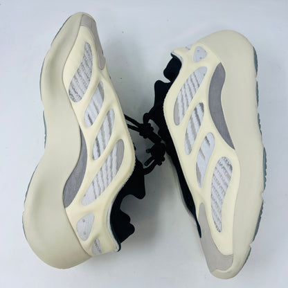 The adidas Yeezy 700 V3 Azael features a futuristic design with a black mesh upper, white and beige sculpted overlays, and an intricate lacing system. It has a sleek, modern look set against a plain white background, showing minimal wear for that fresh out-of-the-box condition.