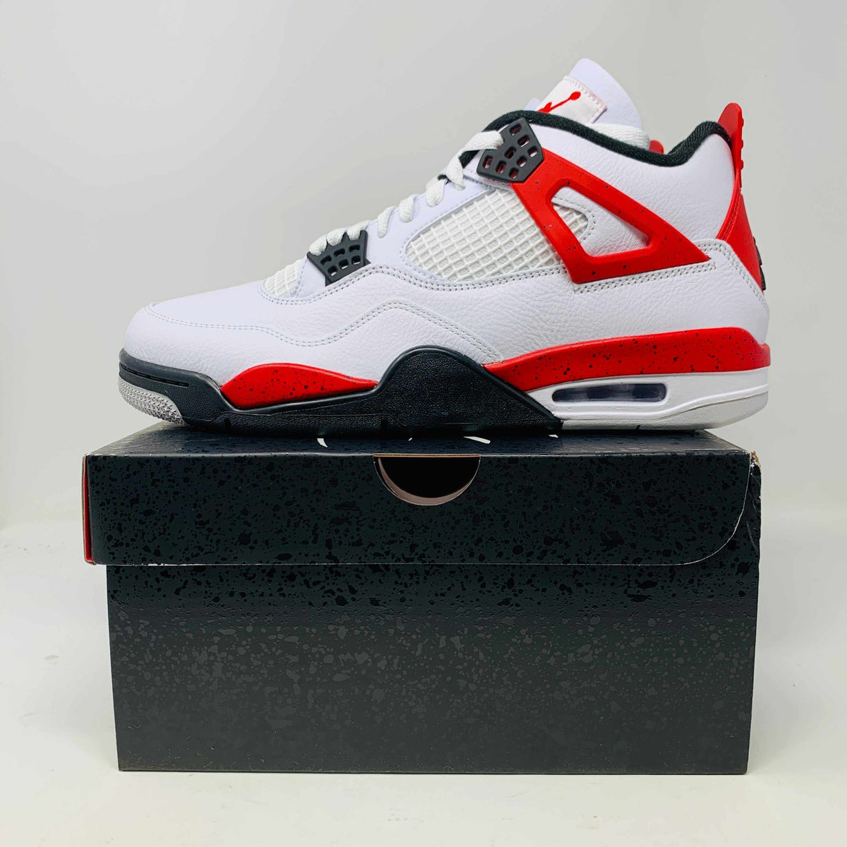 Jordan 4 Retro Red Cement sneaker in white, red, and black on shoebox, 2023 brand new edition