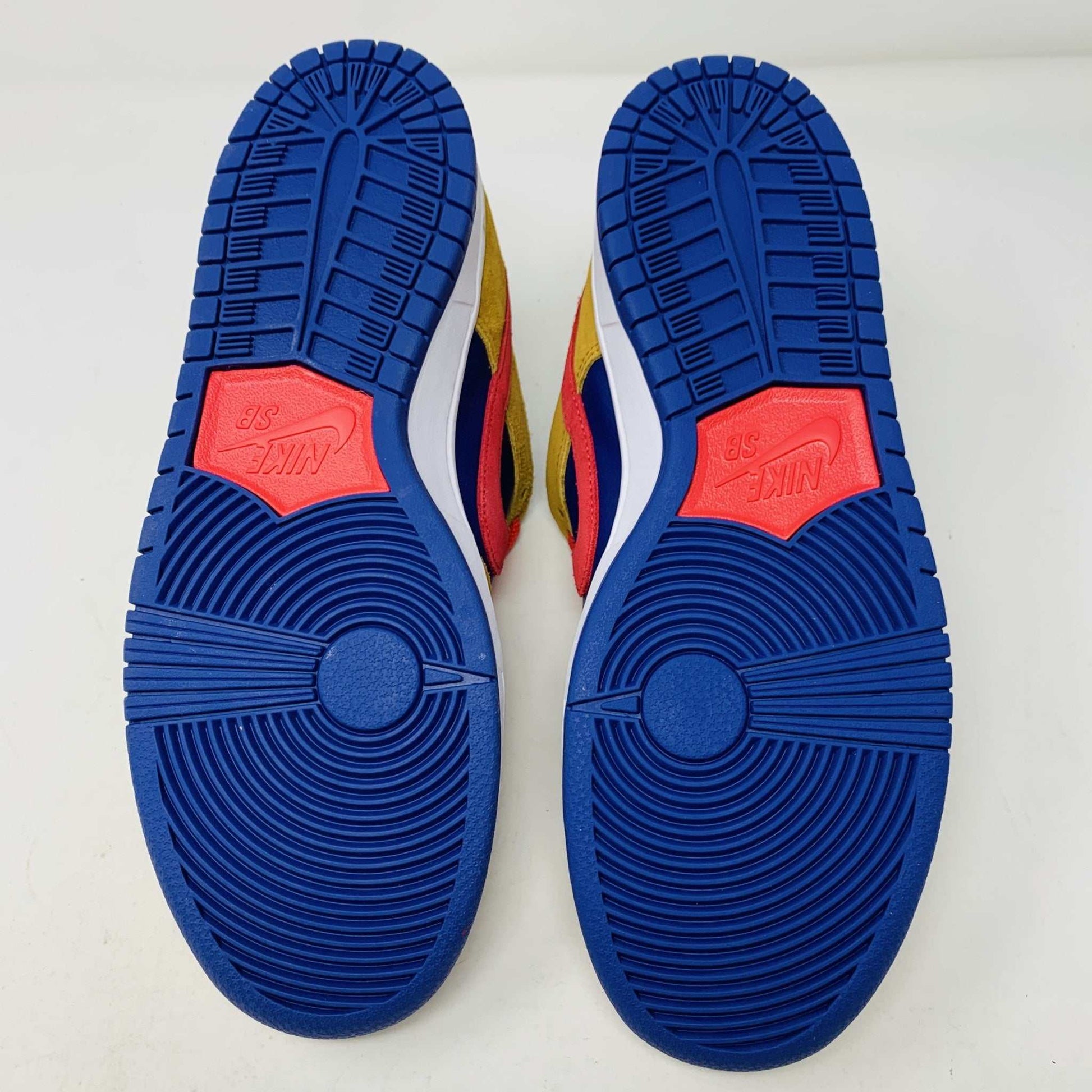 The Nike SB Dunk Low Reverse Papa Bear features a blue and yellow suede upper, a red Swoosh, and orange laces. It comes with extra yellow laces in front of its purple Nike SB box and is 100% authentic.