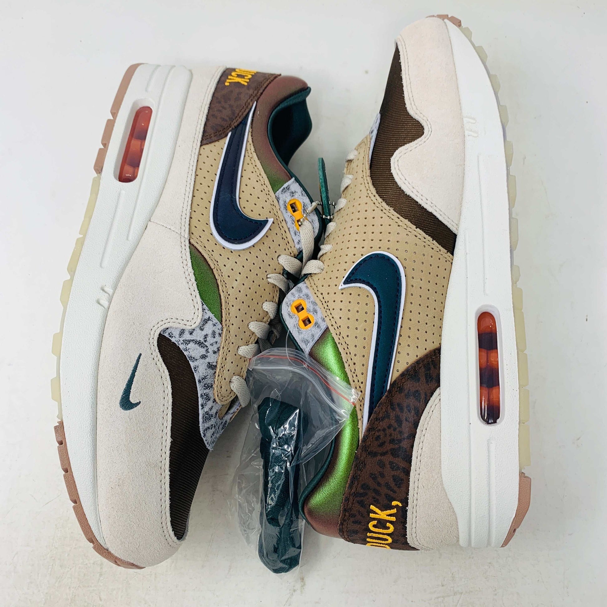 The Nike Air Max 1 87 Premium University of Oregon PE (2024) is a stylish, brand new sneaker featuring a blend of beige, purple, and leopard print with perforated and smooth leather textures. It comes in a vibrant green box and includes a visible air unit in the sole.