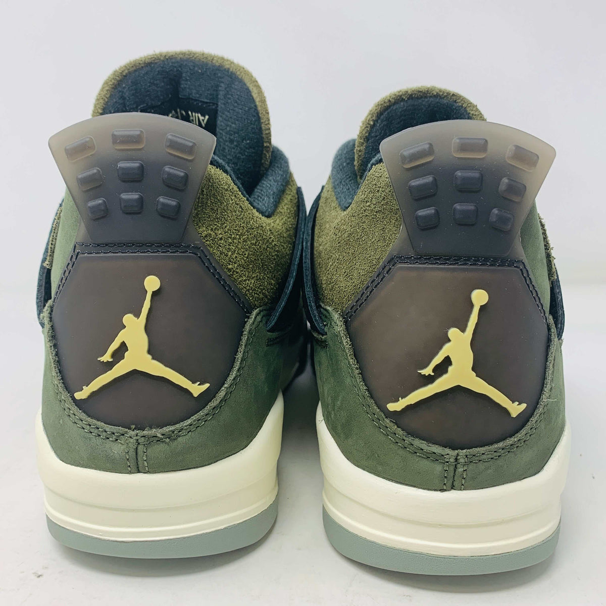 The Jordan 4 Retro SE Craft Medium Olive sneakers feature a blend of green, black, and white with a mesh and suede texture. Elegantly presented on a green shoebox against a white backdrop, they epitomize 100% authentic craftsmanship by Jordan.