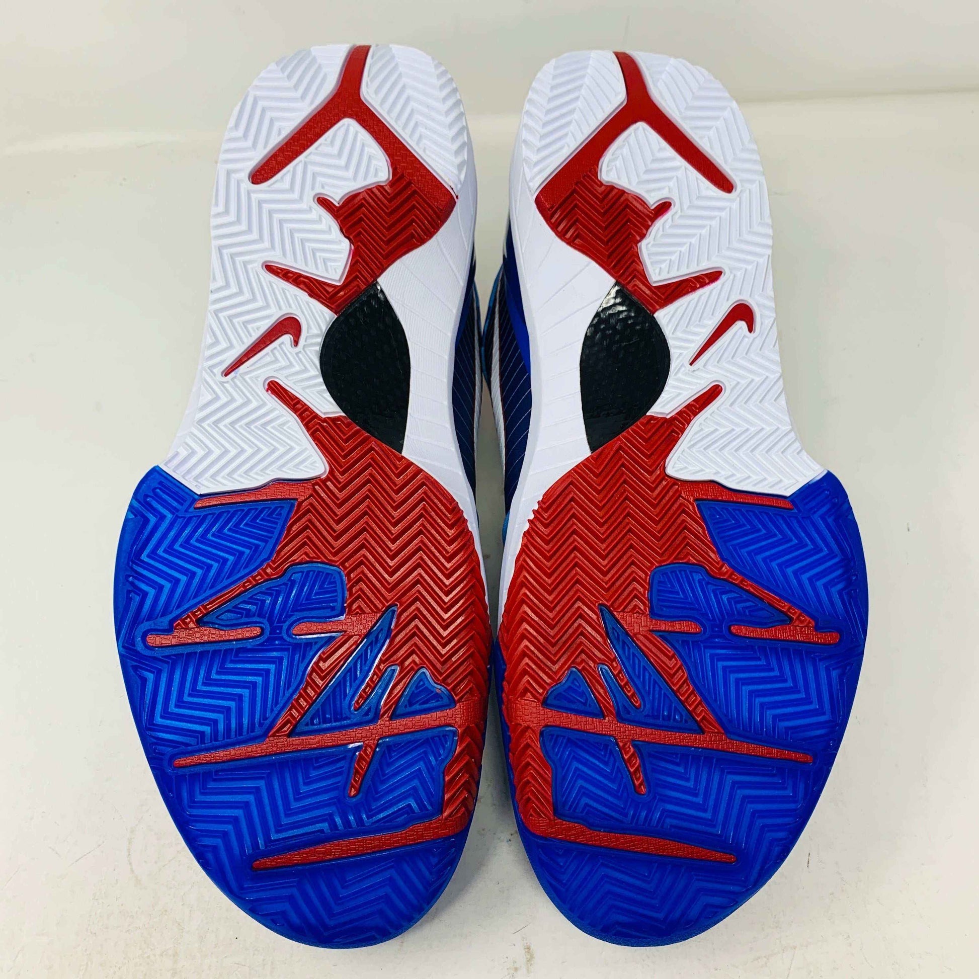 The image displays the soles of Nike Kobe 4 Protro Philly (2024) basketball shoes, featuring a vivid red, white, and blue pattern that captures Philadelphias essence. Zigzag grooves offer excellent traction, enhanced by unique logo designs.