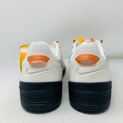 The pristine Nike Field General Union LA Ivory sneakers, in white and orange with black soles, rest on an orange box. Featuring a UNION tag, Nike logo, and a blue sticker with a silhouetted man, theyre perfect for any accessories collection.