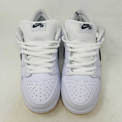 A brand new Nike SB Dunk Low in white with a black swoosh, white laces, and a gum sole rests on a 2023 purple Nike SB shoebox featuring bold white text. The profile view showcases its authentic design.