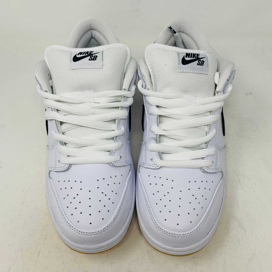 A brand new Nike SB Dunk Low in white with a black swoosh, white laces, and a gum sole rests on a 2023 purple Nike SB shoebox featuring bold white text. The profile view showcases its authentic design.