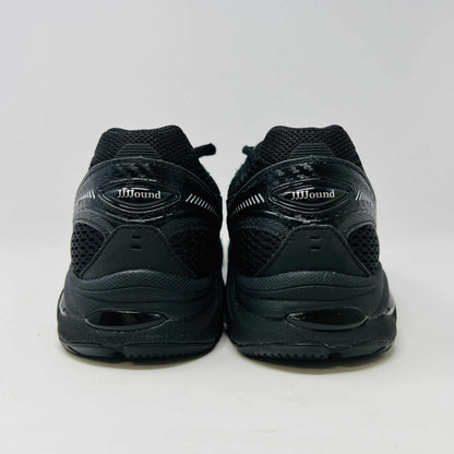 The new ASICS GT-2160 JJJJound Black running shoe sits on its box, featuring extra laces in a clear bag. These authentic shoes present a sleek design with gray detailing and a side text label.