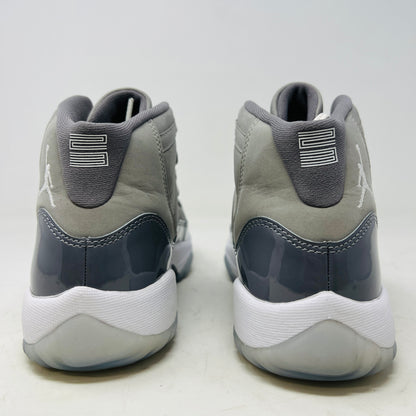 A Jordan 11 Retro Cool Grey (2021) (GS) sneaker by Jordan, in gray and white with a glossy patent leather finish, is displayed on its original Nike shoebox. The box is in good condition featuring a size 6.5Y label and various details, with clean uppers showing light wear and an orange sticker numbered 71.